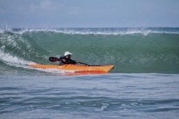 James Roberts sea kayak coach surfing a wave on a Cornish beach