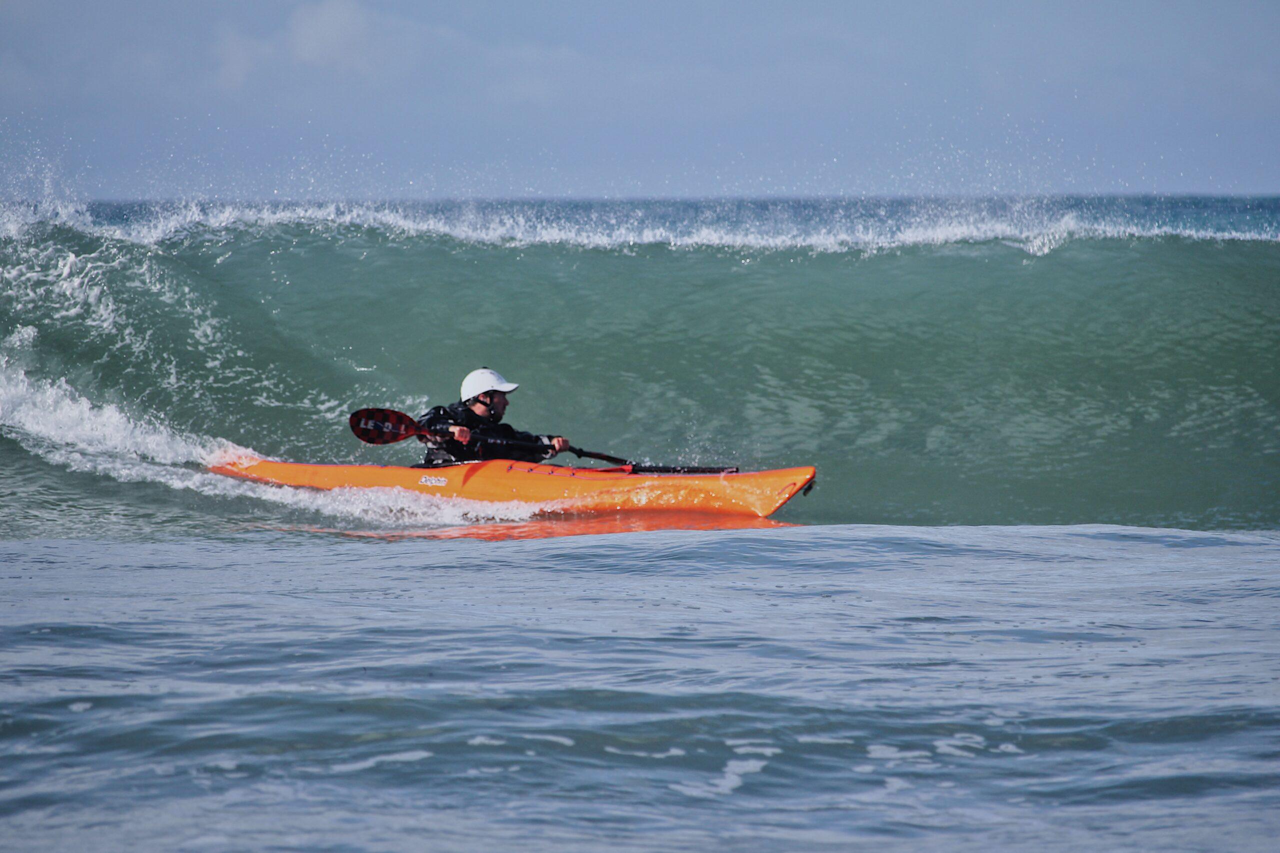 James Roberts sea kayak coach surfing a wave on a Cornish beach